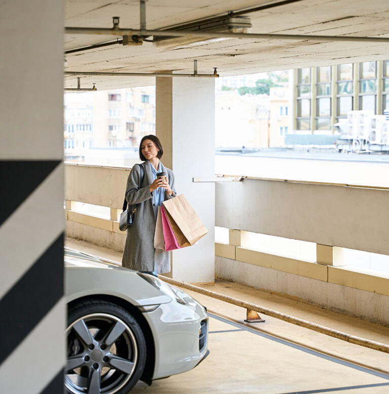 Pretty lady walking at parking lot mall, drinking coffee, shopping, carrying, holding paper bags in hand